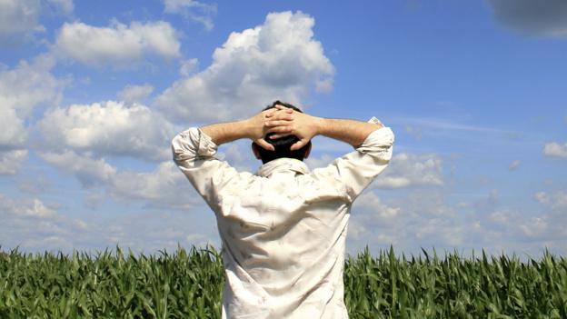 Man with hands behind head, staring at horizon