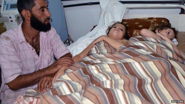 A man sits in a hospital near two children who activists say were affected by nerve gas in the Ghouta region of Damascus, Syria, 21 August 2013