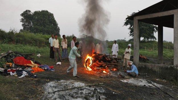 In this Sunday, Oct. 20, 2013 photo, Indian villagers light the pyre of Shiv Bachan, who died after drinking toxic bootleg liquor, on Raj Ghat in Azamgarh district