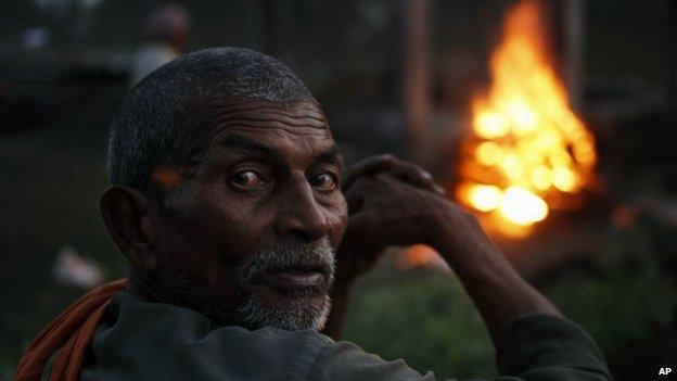 In this Sunday, Oct. 20, 2013 photo, an Indian villager attends the funeral of Shiv Bachan, who died after drinking toxic bootleg liquor, on Raj Ghat in Azamgarh district