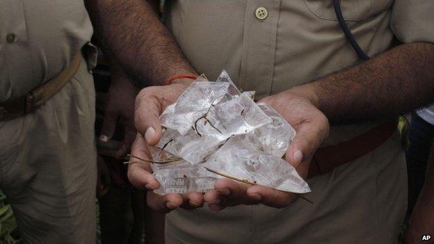 An Indian policeman displays packets of illegal bootleg liquor seized from a well at Narawn village in Azamgarh district