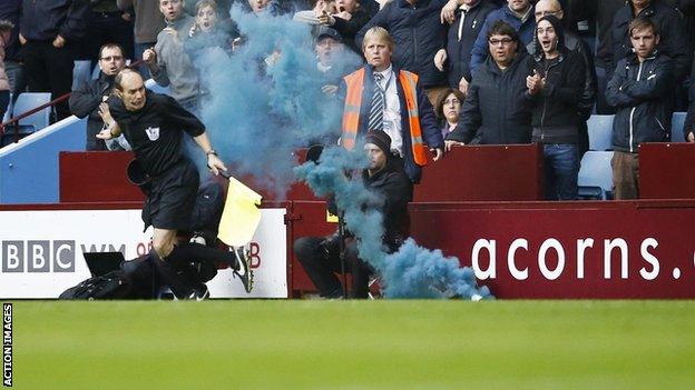 Assistant referee David Bryan is struck by a flare during the Aston Villa v Tottenham Hotspur match