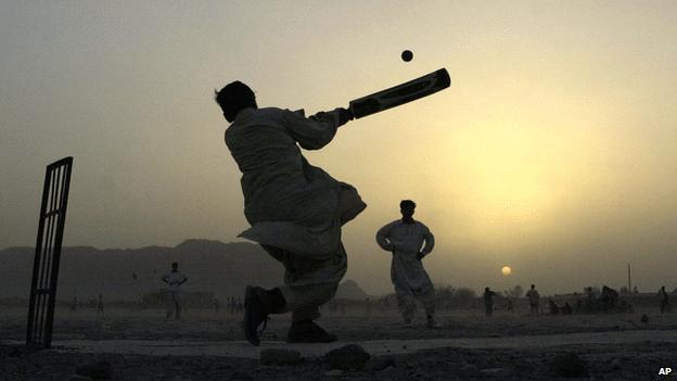 A young boy sends the cricket ball flying as the sun sets in the west in Kandahar in 2002