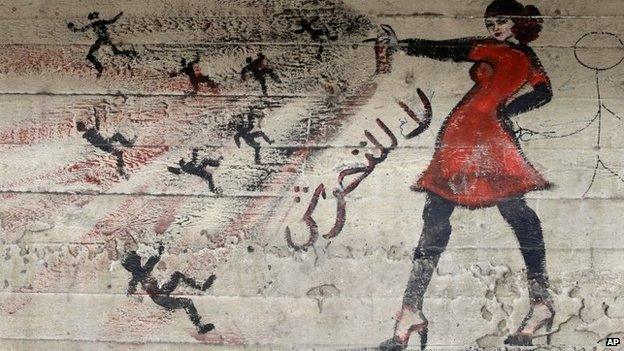 A mural showing a woman spraying a number of men with the slogan: "No to harassment" in Cairo (May 2013)