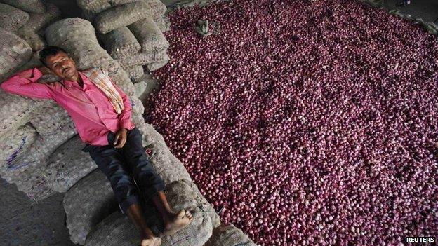 A labourer rests on sacks filled with onions at a wholesale vegetable market in the northern Indian city of Chandigarh October 24, 2013