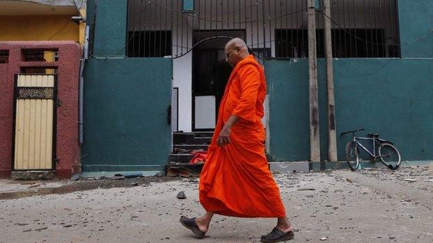 A Sri Lankan Buddhist monk walks past a vandalized mosque in Colombo, Sri Lanka, Sunday, Aug. 11, 2013.