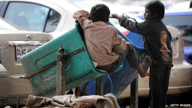 Impoverished Indian children play in empty dustbins