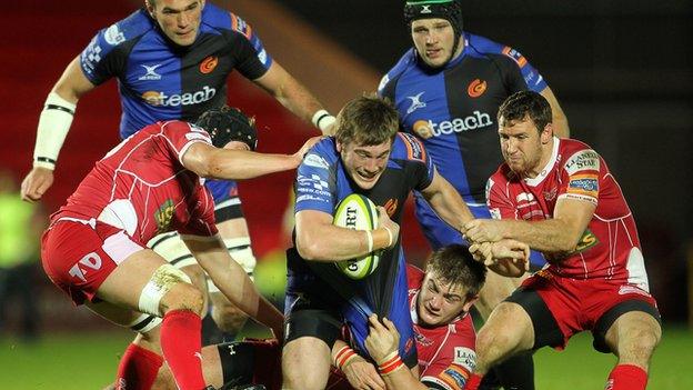 Scarlets’ Richard Kelly, Craig Price and Adam Warren tackle Hugh Gustafson of Newport Gwent Dragons