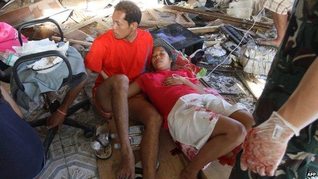 A 21-year-old woman lies exhausted on the debris-covered floor at a makeshift medical facility in Tacloban after giving birth to a baby girl