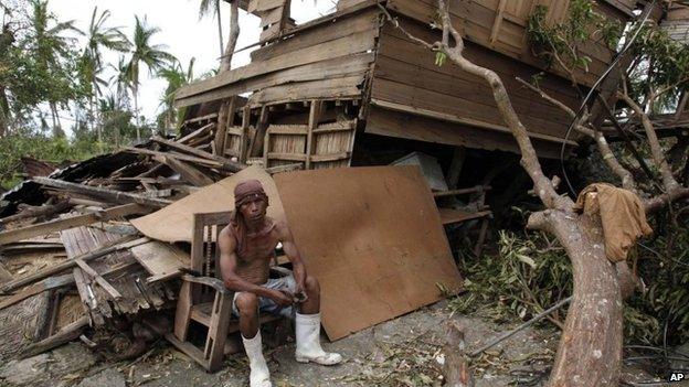 A man salvages wood from his damaged house after the typhoon hit Tabogon town in Cebu province, 11 November 2013