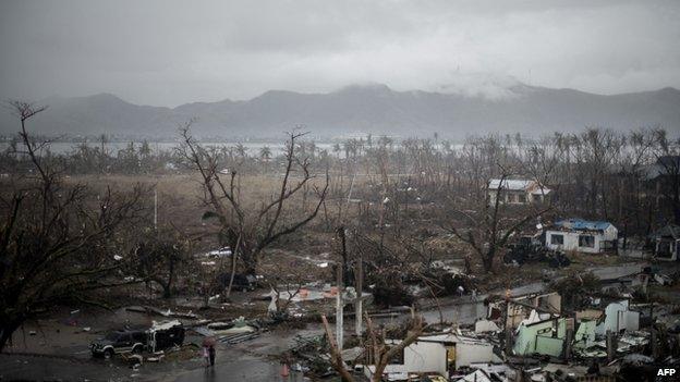 Two typhoon victims walk a road surrounded by a devastated land outside the airport in Tacloban, on the eastern island of Leyte on 12 November 2013