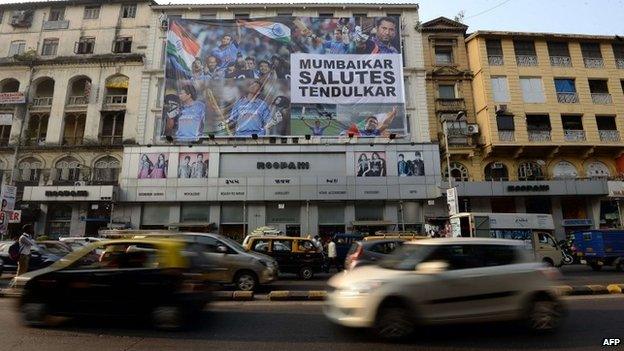 Vehicles journey past a huge banner saluting Indian cricketer Sachin Tendulkar on the facade of a shop in Mumbai on November 13, 2013