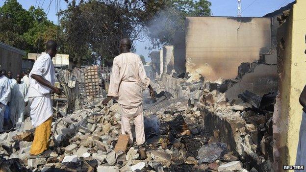 Residents watch as two men walk amid rubble after Boko Haram militants raided the town of Benisheik, west of Borno state capital, Maiduguri, 19 September 2013
