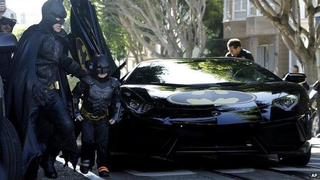 Miles Scott, dressed as Batkid, exits the Batmobile with Batman to save a damsel in distress in San Francisco, on 15 November 2013