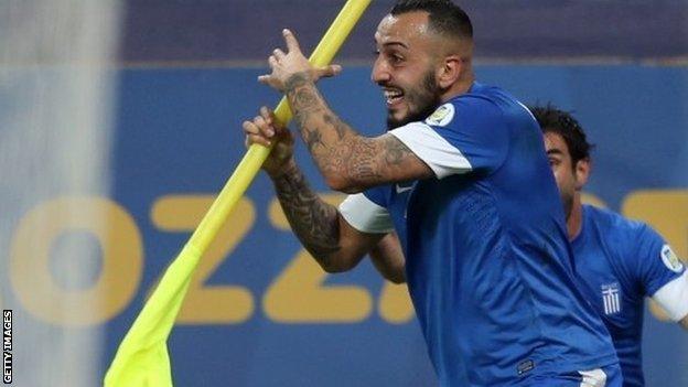 Konstantinos Mitroglou celebrates with the corner flag after putting Greece ahead