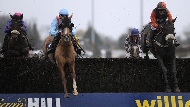 Riders jump a fence at the William Hill King George VI Chase