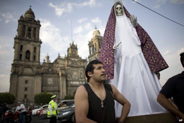 Man stands by statue of Santa Muerte in front of cathedral