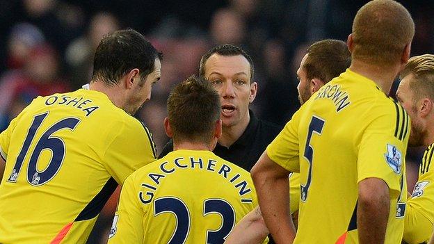 Referee Kevin Friend is surrounded by Sunderland players after sending off Wes Brown