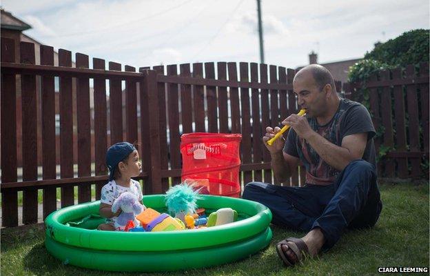 Jiri plays with baby Roman in the front garden of their home