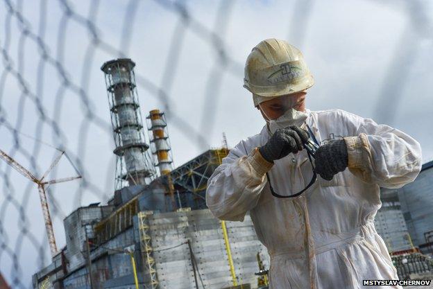 A man in white radiation protection gear in front of the nuclear reactor