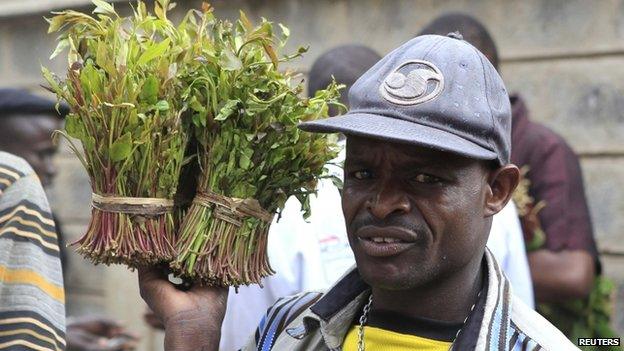 A vendor walks away with bundles of khat leaves from an open air wholesale market in Kenya's capital Nairobi - July 2013