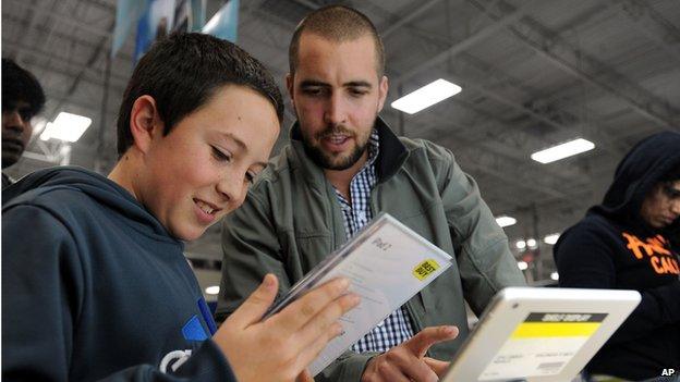 Sabastian Valenzuela, left, and his older brother Alberto compare prices for iPad tablets at a Best Buy late in the evening on Thanksgiving Day, Thursday, Nov. 28, 2013, in Dunwoody, Ga