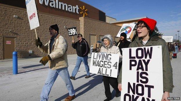 A group of protesters walk through the Walmart retail store parking lot on Black Friday in Elgin, Illinois, ON 29 November 2013