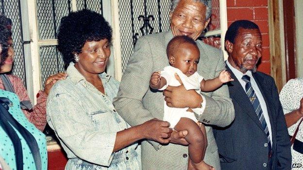 Nelson Mandela and his then-wife Winnie play with their grandchild Bambata at their Soweto home 21 February 1990