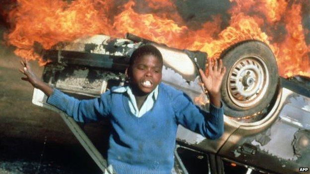 A South African boy pictured on 10 July 1985 in Duduza township by a car burnt during an anti-apartheid riot