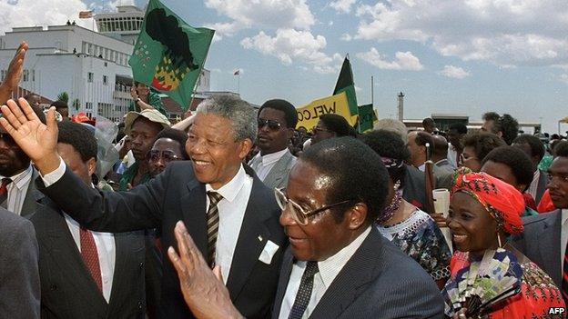 Nelson Mandela is welcomed by Zimbabwean president Robert Mugabe (2nd L) as he arrives in Zimbabwe, 4 March 1990, in Harare