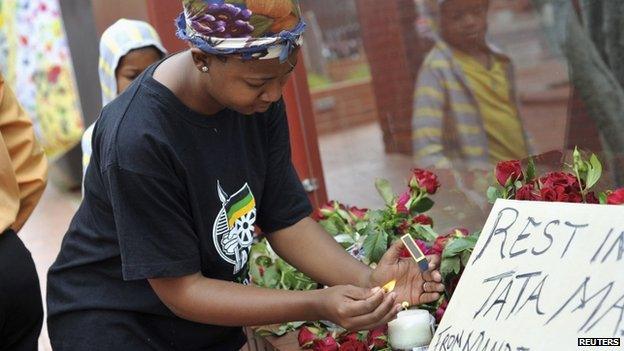 A woman lights a candle during a gathering of mourners on Vilakazi Street in Soweto, where the former South African President Nelson Mandela resided when he lived in the township, 6 December 2013