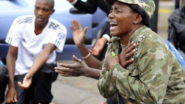 People react during a gathering of mourners on Vilakazi Street in Soweto where the former South African President Nelson Mandela resided when he lived in the township, 6 December 2013