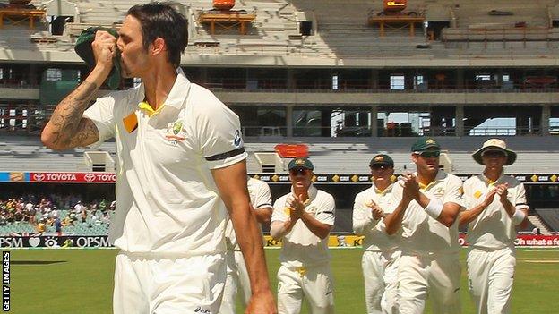 Mitchell Johnson kisses the badge on his cap as he leads Australia off at tea