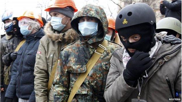 People wear helmets and masks as they attend the rally.