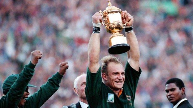 South African rugby captain Francois Pienaar raises the trophy after receiving it from Nelson Mandela (24 June 1995)