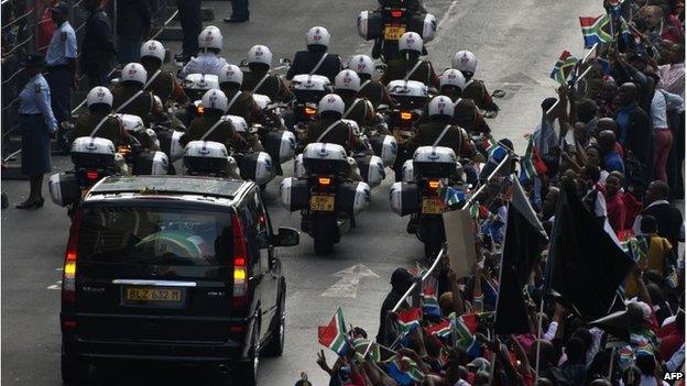 People cheer as the body of Nelson Mandela is driven past in Pretoria on December 11