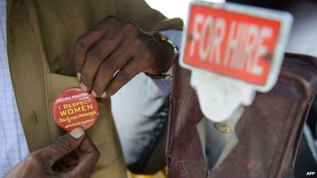 An Indian auto driver pins on an "I respect women" badge from the Andhra Pradesh Tourism Department during World Tourism Day celebrations in Hyderabad