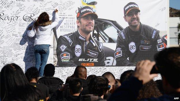 A woman signs a memorial to Paul Walker and friend Richard Rodas