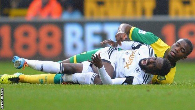 Swansea City's Nathan Dyer in pain after he fell heavily under Norwich City's Sebastien Bassong.