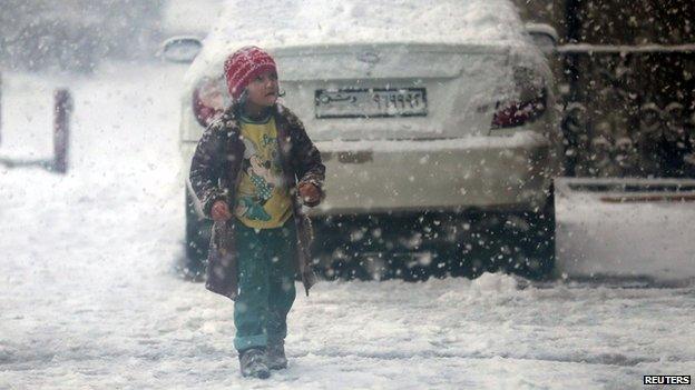 Child walks during snow fall in the Duma neighbourhood of Damascus (13 December 2013)