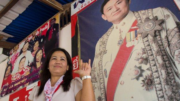 Khamsaen Chaithep, wife of the village chief in Nhong Huu Ling, stands by a poster of Thaksin Shinawatra