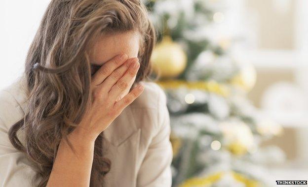 Woman looking stressed in front of Christmas tree