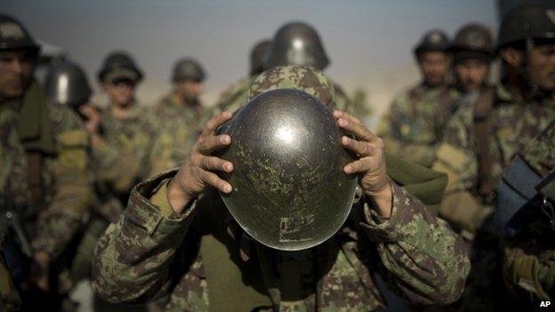 An Afghan army soldier adjusts his helmet as he lines up with others at a training facility in the outskirts of Kabul, Afghanistan