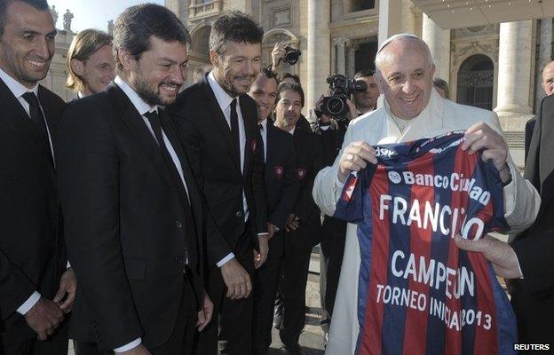 Pope Francis holds a jersey of Argentine soccer team San Lorenzo, given to him as a gift from members of the team, during the Wednesday general audience in St Peter's Square at the Vatican on 18 December, 2013