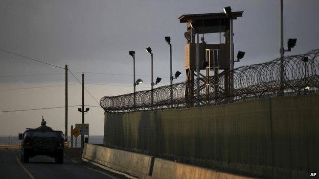 A US trooper stands in the turret of a vehicle with a machine gun, left, as a guard looks out from a tower at the detention facility of Guantanamo Bay