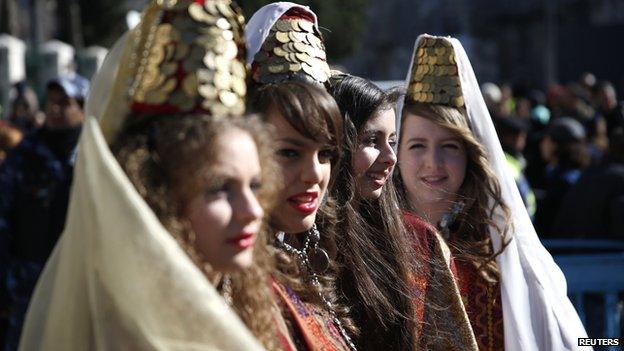 Young women wearing traditional Palestinian costumes take part in a Christmas procession at Manger Square in front of the Church of the Nativity, the site revered as the birthplace of Jesus, in the West Bank town of Bethlehem