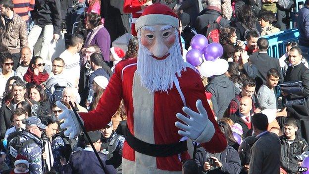 Christian pilgrims gather near a Santa Claus dummy at Manger Square in Bethlehem