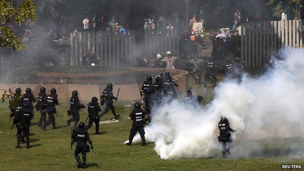 Riot policemen run after anti-government protesters trying to enter the Thai-Japan youth stadium in central Bangkok