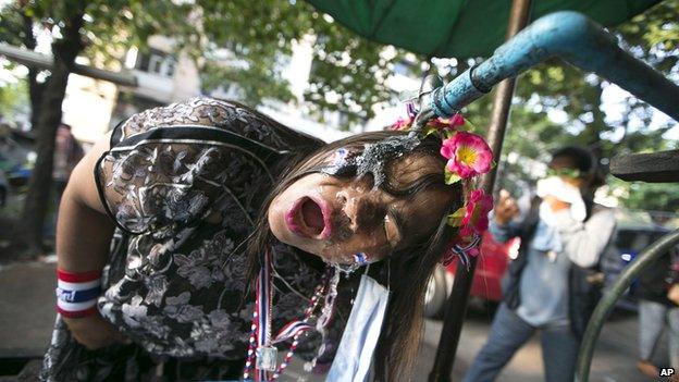 A Thai anti-government protester washes tear gas from her face during a clash with riot policemen at a sport stadium in Bangkok