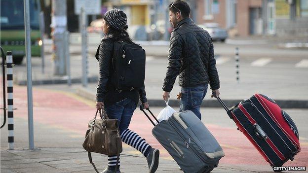 A young Roma couple walk with suitcases outside the main bus station on December 7, 2013 in Sofia, Bulgaria.